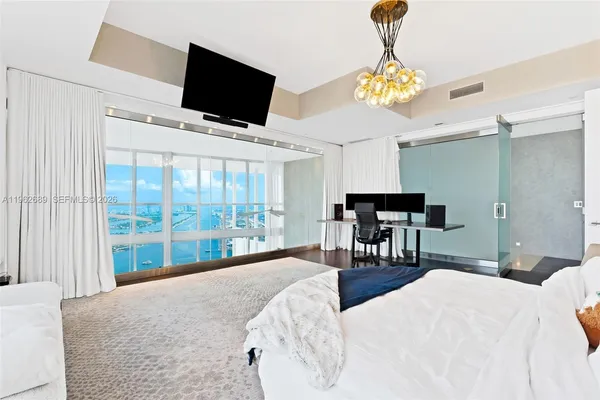 a spacious bedroom with a large bed and a chandelier