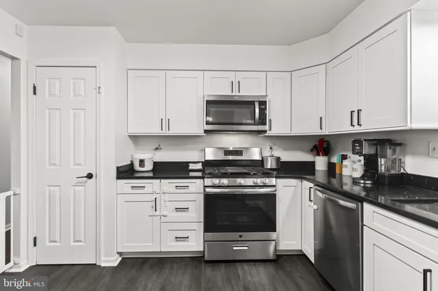 a kitchen with stainless steel appliances granite countertop grey cabinets a stove a sink and dishwasher