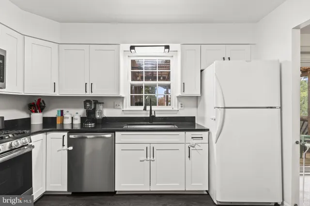 a kitchen with granite countertop white cabinets and white appliances