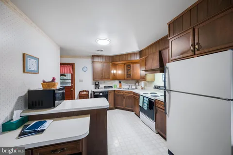 a kitchen with stainless steel appliances granite countertop a refrigerator a sink dishwasher a stove and a refrigerator with wooden floor