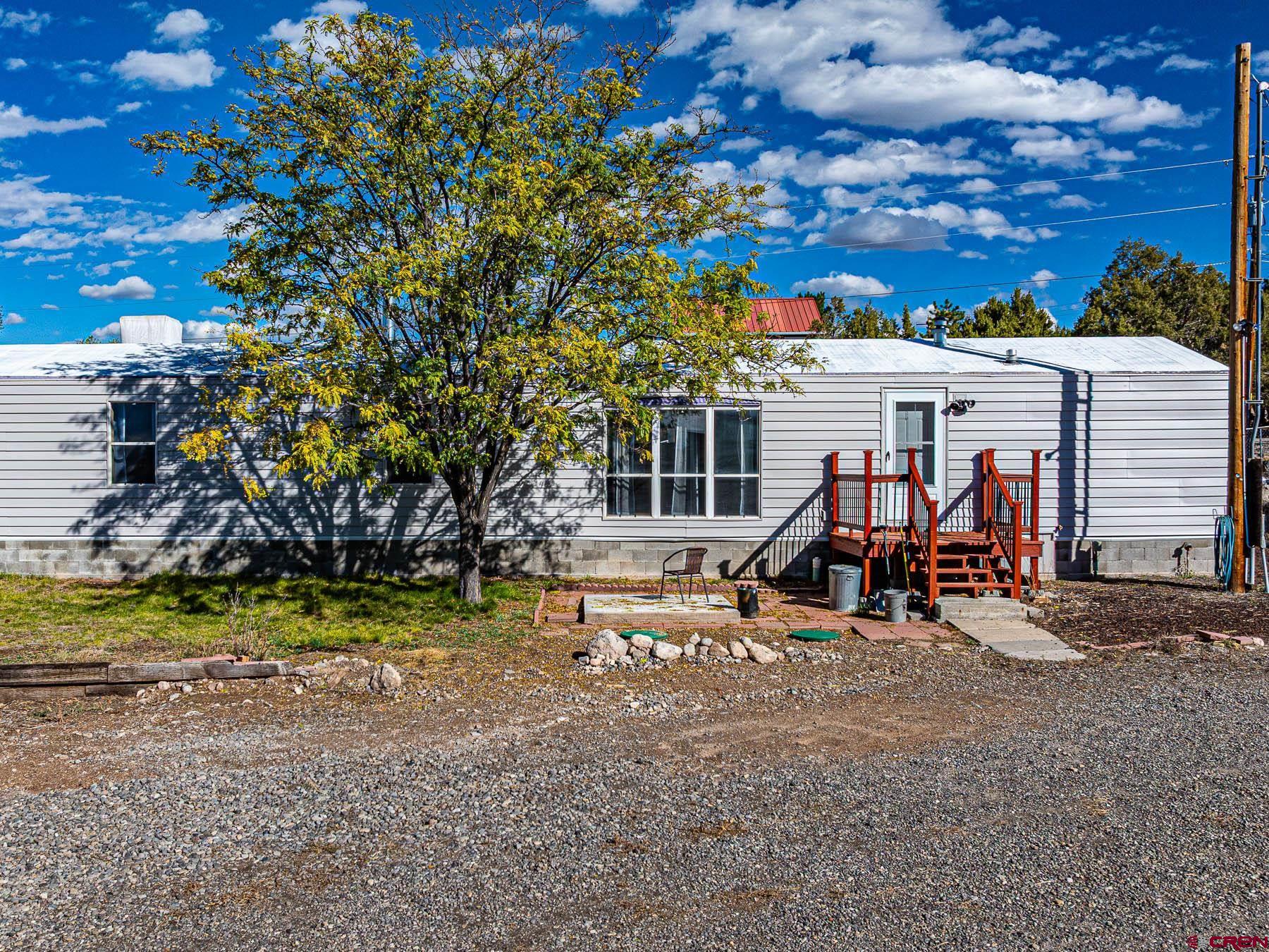 17199 2550th Road Cedaredge, CO 81413 - Photo 2 of 38 a view of a wooden house with a yard and sitting area