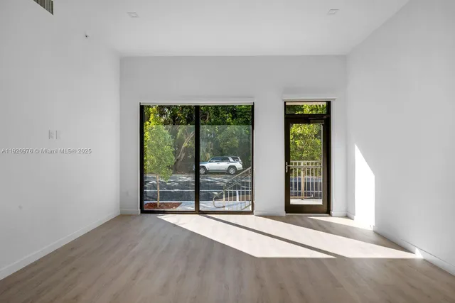 an empty room with wooden floor and outdoor view