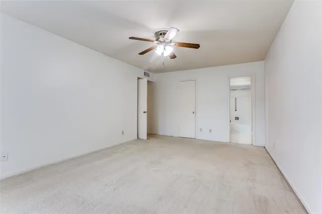 an empty room with windows and chandelier fan