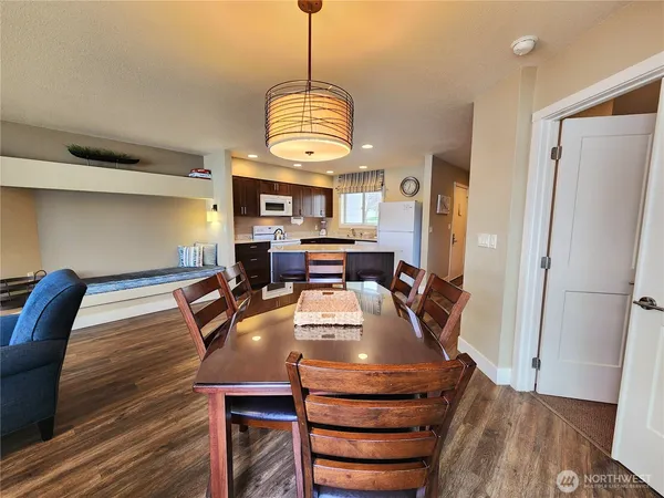 a dining room with wooden floor a chandelier a wooden table and chairs