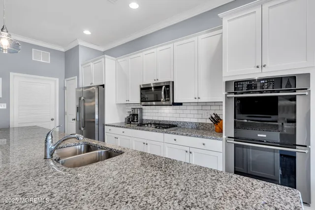 a kitchen with stainless steel appliances granite countertop a refrigerator a sink dishwasher a couches and chairs with wooden floor