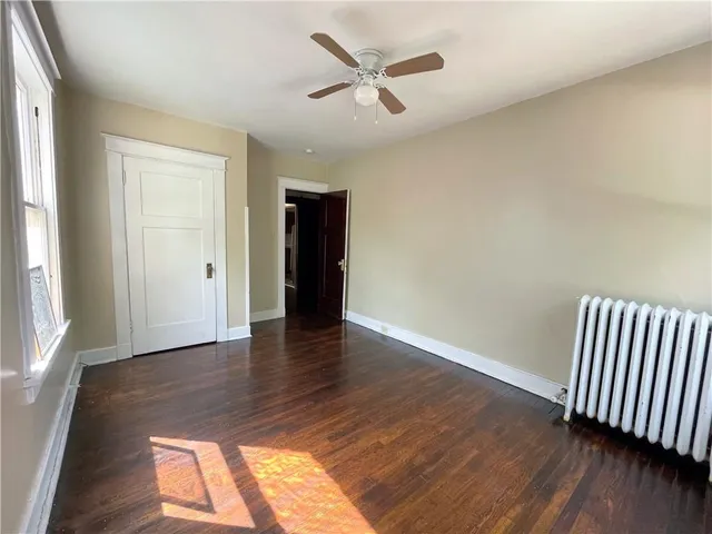 an empty room with wooden floor and a ceiling fan