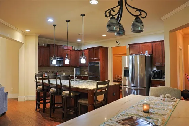 a kitchen with stainless steel appliances kitchen island granite countertop a table chairs and a refrigerator