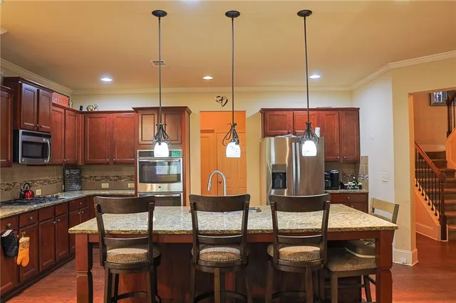 a kitchen with stainless steel appliances kitchen island granite countertop a table chairs and a refrigerator