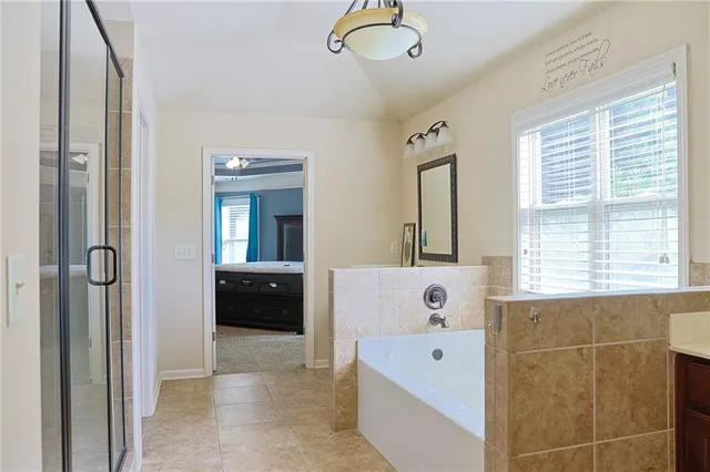 a en suite spacious bathroom with a tub double vanity and windows