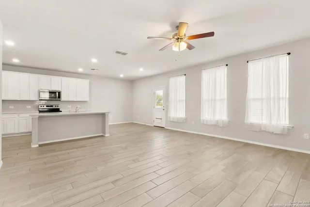 a view of an empty room with window and wooden floor