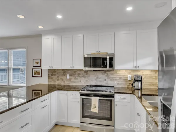 a kitchen with stainless steel appliances granite countertop a stove a sink and a microwave