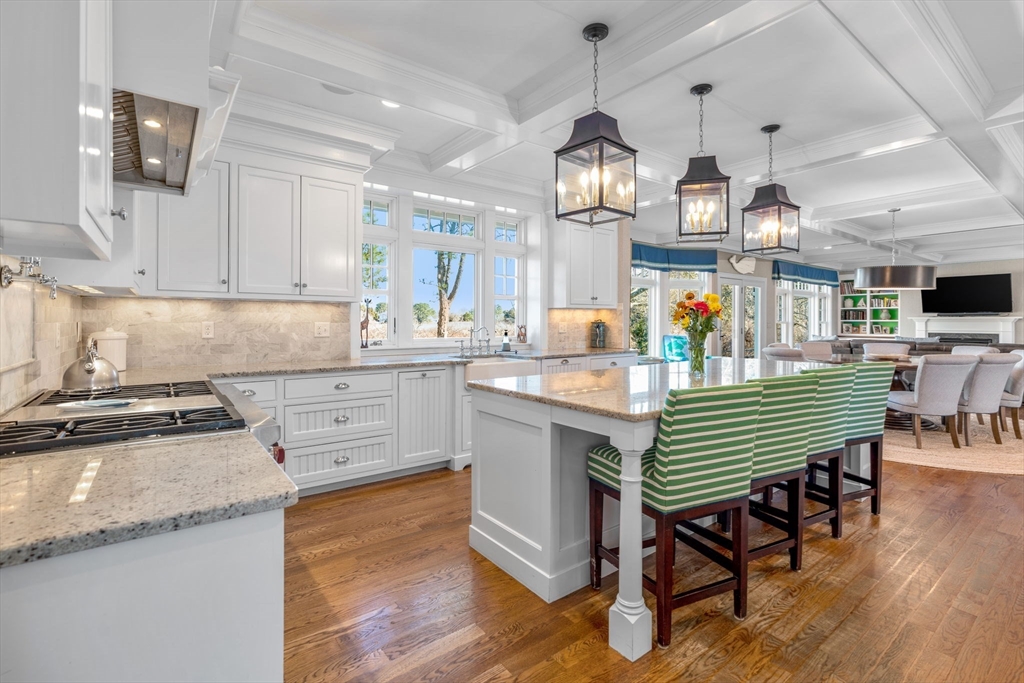 67 Uncle Alberts Drive Chatham, MA 02633 - Photo 3 of 41 a kitchen with granite countertop a stove a sink a dining table and chairs with wooden floor