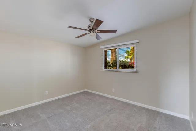 an empty room with windows and ceiling fan