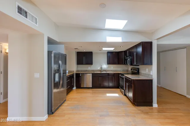 a large kitchen with stainless steel appliances kitchen island granite countertop a refrigerator and a stove top oven