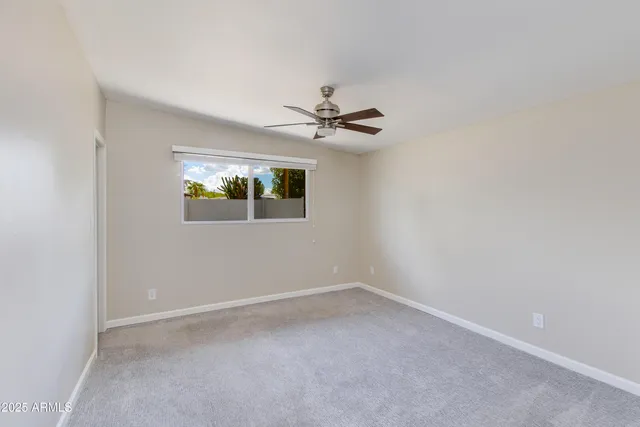 an empty room with a window and a ceiling fan