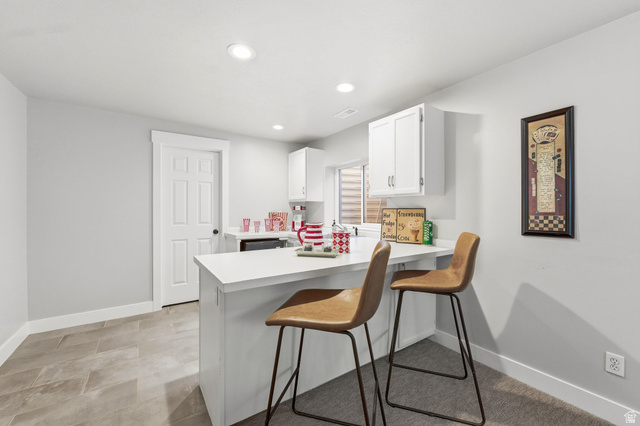 1405 Vintry Lane Murray, UT 84121 - Photo 27 of 44 Kitchenette featuring a white countertop bar, upper cabinetry, recessed lighting, and a white six-panel door
