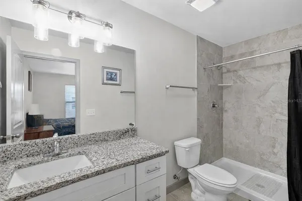 a bathroom with a granite countertop sink a toilet and shower