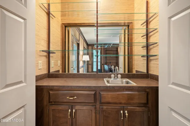 a view of a hallway with wooden floor and a bathroom