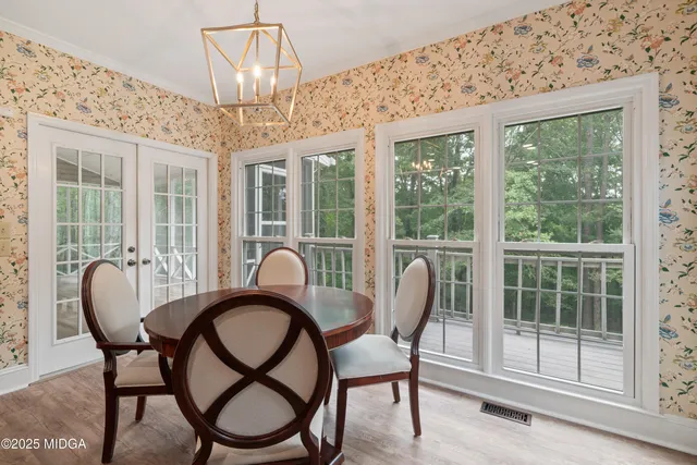 a view of a white house with a large windows and a yard with plants and large trees