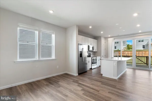 a kitchen with stainless steel appliances granite countertop a refrigerator a sink a stove and white cabinets with wooden floor