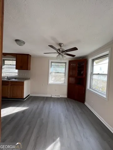 a view of an empty room with a kitchen and a window
