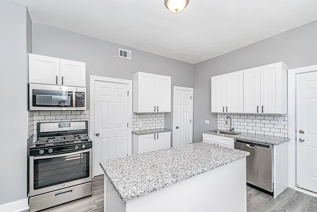 a kitchen with stainless steel appliances kitchen island granite countertop a stove and a sink