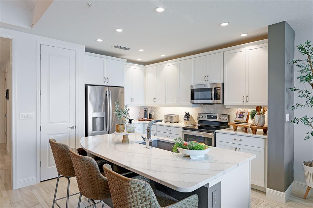 10520 Boardwalk Loop, Unit 704 Lakewood Ranch, FL 34202 - Photo 12 of 55 a kitchen with stainless steel appliances granite countertop a dining table chairs refrigerator and microwave