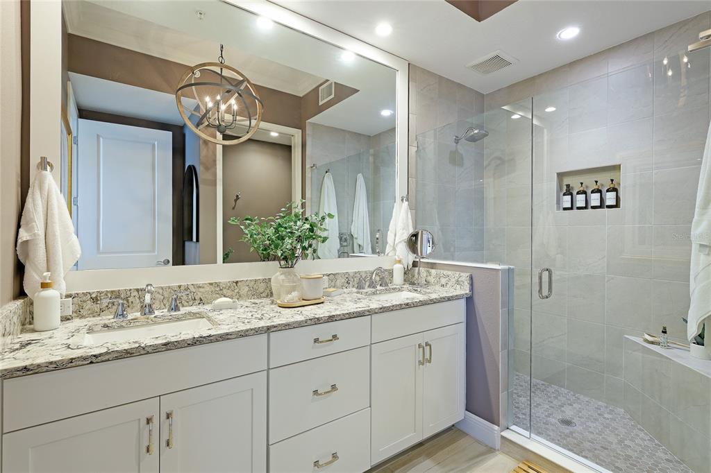 10520 Boardwalk Loop, Unit 704 Lakewood Ranch, FL 34202 - Photo 21 of 55 a bathroom with a granite countertop sink a mirror and a shower