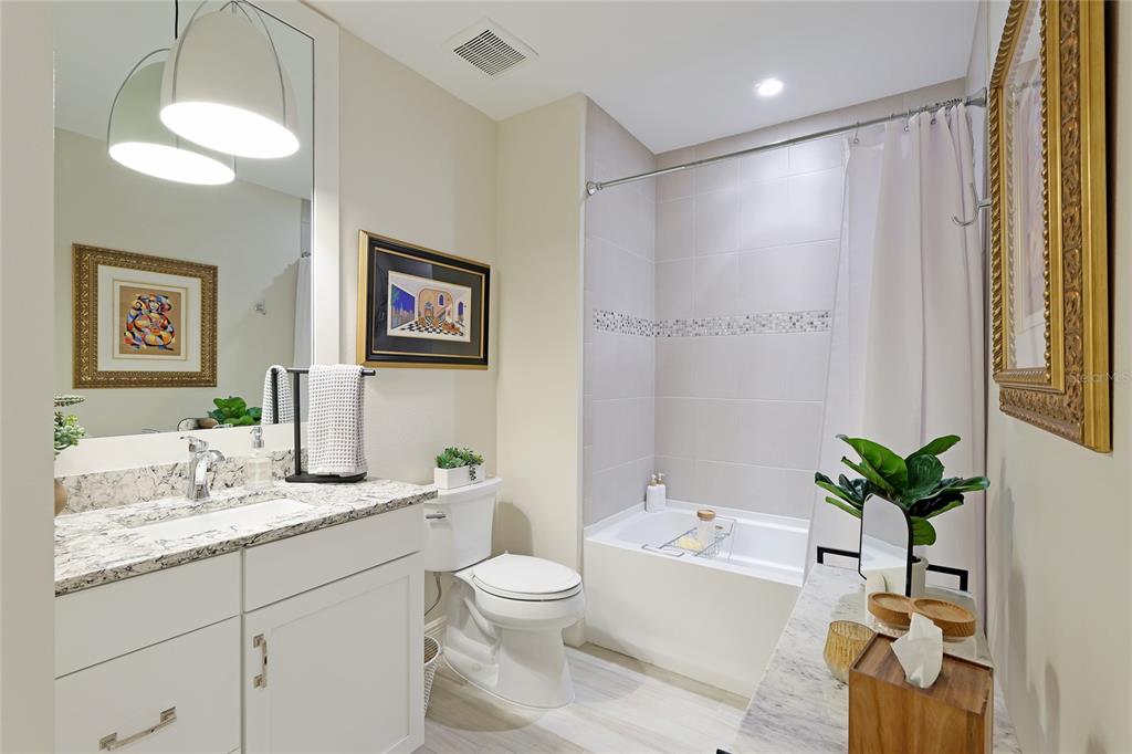 10520 Boardwalk Loop, Unit 704 Lakewood Ranch, FL 34202 - Photo 27 of 55 a bathroom with a granite countertop sink a toilet a mirror a vanity a bathtub and shower