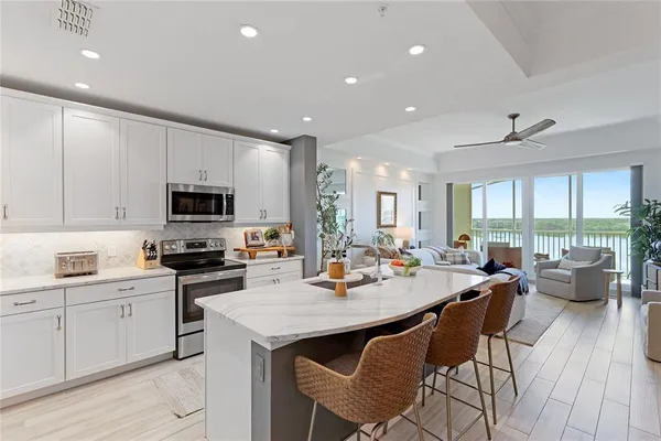 a kitchen with stainless steel appliances granite countertop a dining table chairs refrigerator and microwave
