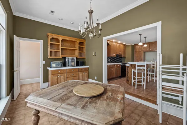 a dining room with furniture a chandelier and kitchen view