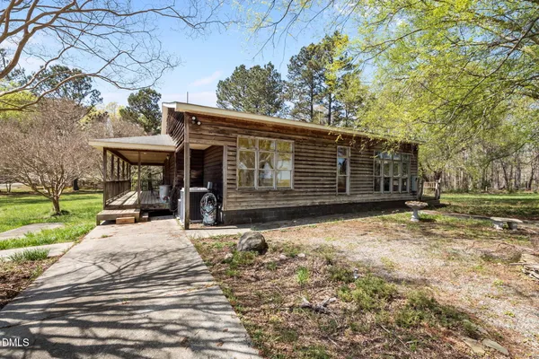 a backyard of a house with large trees and a wooden fence