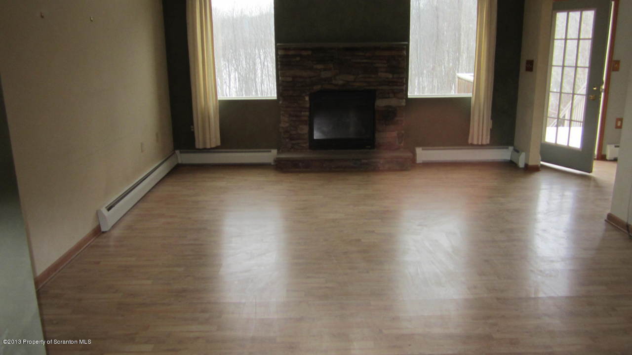 420 Municipal Road Dallas, PA 18612 - Photo 3 of 11 an empty room with wooden floor fireplace and windows
