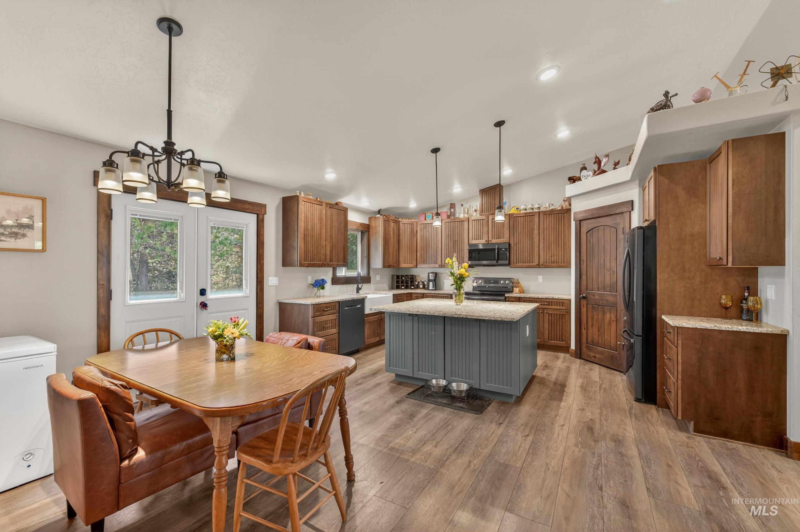 13388 Norwood Road McCall, ID 83638 - Photo 12 of 44 Open-concept kitchen featuring wood-finish flooring, a central island with a light-colored countertop, abundant cabinetry, and pendant lighting