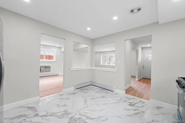 a view of a hallway to room with wooden floor and windows