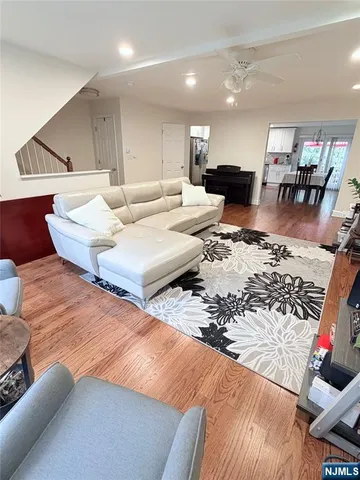 a living room with furniture and a dining table with wooden floor