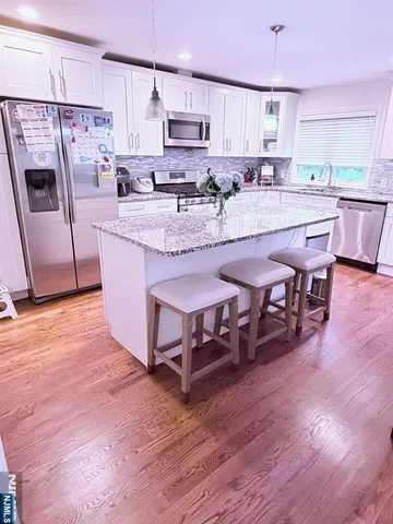 a kitchen with stainless steel appliances granite countertop a table chairs sink refrigerator and microwave