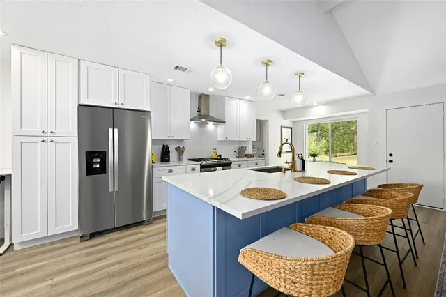 a kitchen with stainless steel appliances granite countertop a kitchen island a table chairs and a refrigerator