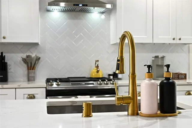 a kitchen with stainless steel appliances kitchen island granite countertop a stove a sink and white cabinets