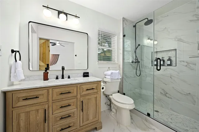 a bathroom with a toilet a sink shower and mirror