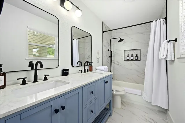 a bathroom with a double vanity sink toilet mirror and bathtub