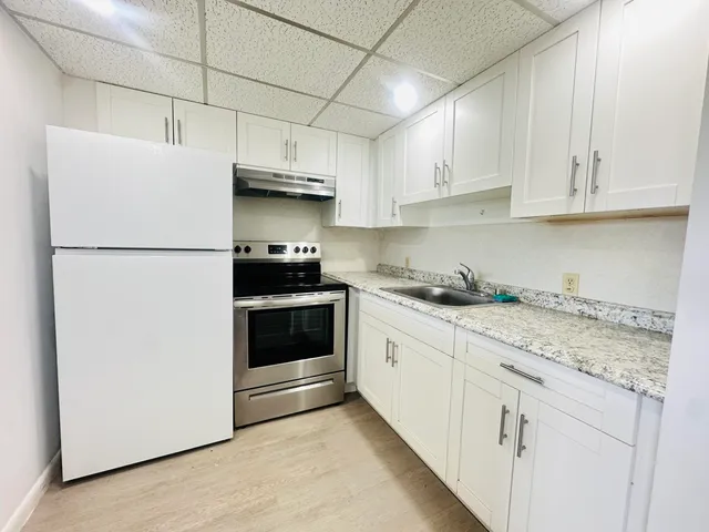 a kitchen with granite countertop white cabinets and white appliances