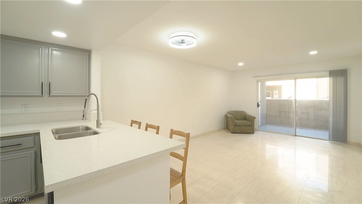 8070 West Russell Road, Unit 1099 Las Vegas, NV 89113 - Photo 12 of 31 A well-appointed kitchen with an integrated sink and light-toned countertops opens to a living area with patio access.