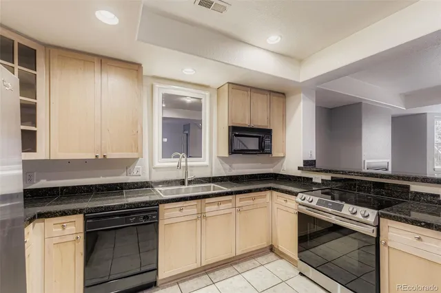 a white kitchen with granite countertop a stove and a sink