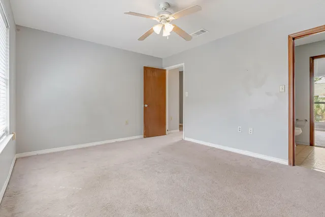 a view of an empty room and chandelier fan
