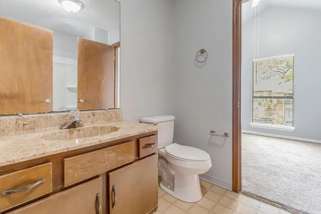 a bathroom with a granite countertop sink a toilet and a mirror