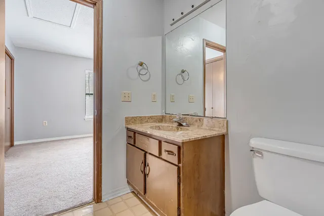 a bathroom with a granite countertop sink a toilet a mirror and shower