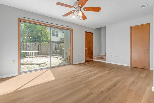 a view of an empty room with window and wooden floor