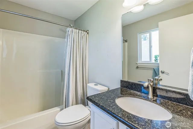 a bathroom with a granite countertop sink toilet a mirror and shower