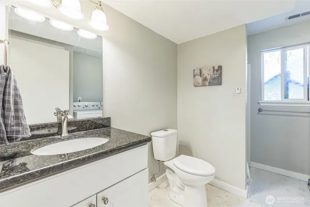 a bathroom with a granite countertop sink toilet and a mirror